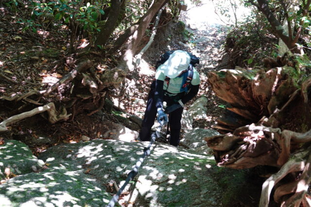 屋久島ハイキングの鎖場を慎重に通過するハイカー