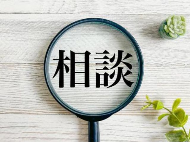 虫眼鏡で「相談」という文字を拡大している、明るい木目背景のイメージ画像。ツアー内容の事前相談。