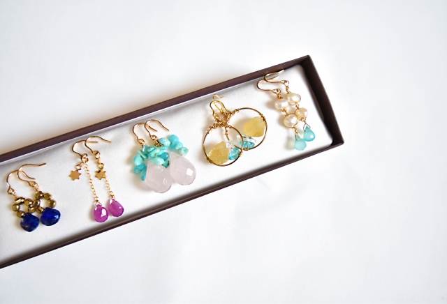 金色のアクセントが施された天然石のイヤリングが並べられた長方形の箱