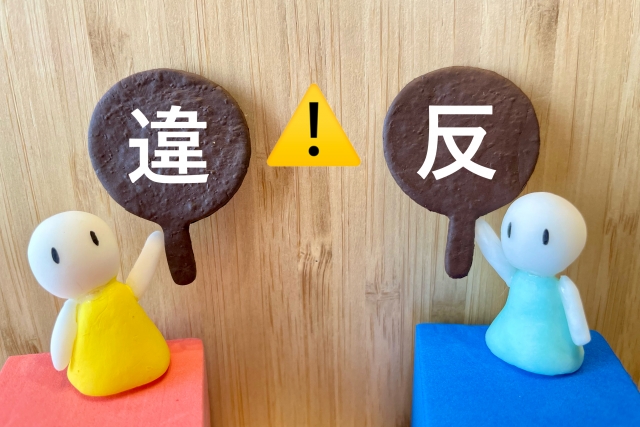 「違」「反」と書かれたプレートを持つ人形と、中央に配置された黄色い注意喚起の警告マーク