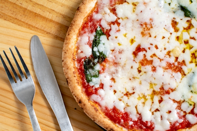 マルゲリータピザの近接ショット、溶けたモッツァレラチーズとバジルの葉が特徴