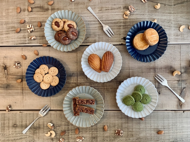 さまざまなクッキーとペストリーが丸いお皿に並べられ、木製のテーブルにフォークとともに置かれている