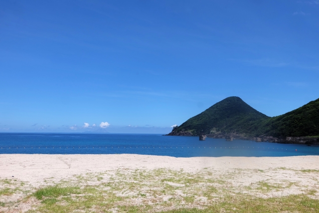 青い空と遠くに山が見える広々とした砂浜、穏やかな一湊海水浴場の風景