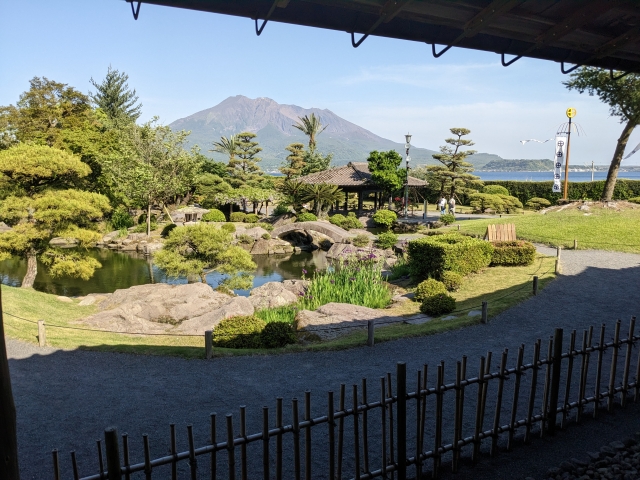 池の周りに石庭と緑の木々が配置された仙巌園。遠くに桜島が見える