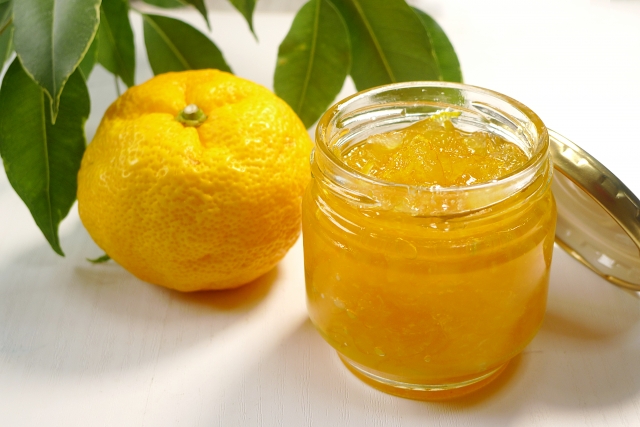 自家製のゆずジャムが入った瓶と、背景に葉が添えられた柚子