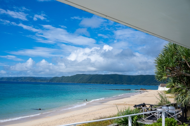 奄美大島の美しいビーチと遠くの山々、澄んだ青い海が広がる風景