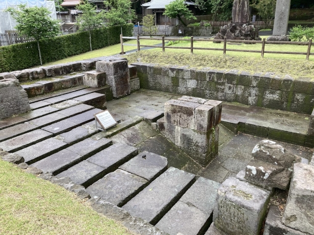 広い空間に並べられた石ブロックと案内板が置かれている旧集成館反射炉跡