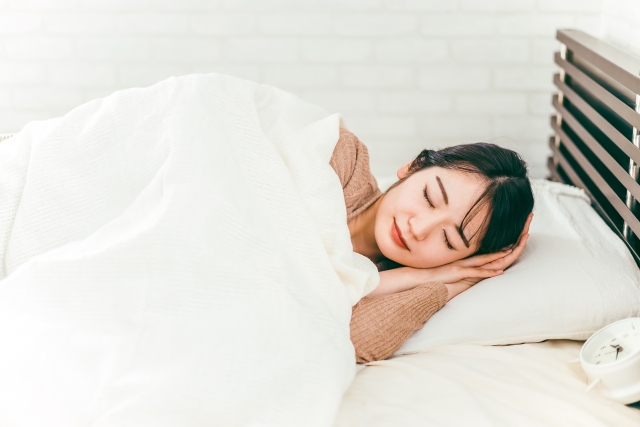 白いベッドで気持ちよさそうに眠る女性