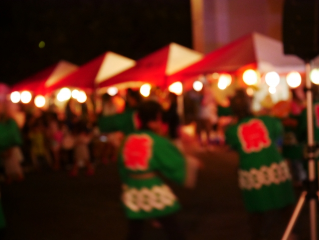 夜祭りで踊る法被姿の人々と屋台