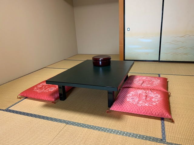 畳敷きの和室に座卓と赤い座布団が置かれた民宿の客室