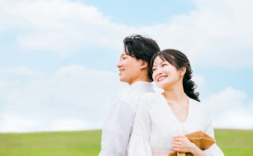 在蓝天之下依偎在一起、面带微笑的新婚夫妇
