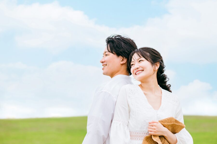 在蓝天之下依偎在一起、面带微笑的新婚夫妇
