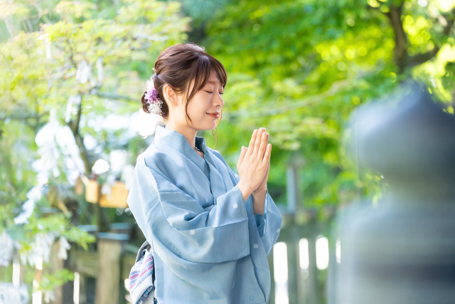 神社で参拝をする浴衣姿の女性